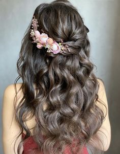 the back of a woman's head with long hair and flowers in her hair