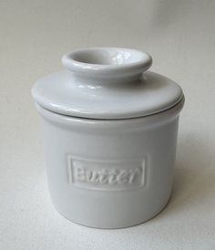 a white ceramic jar with a lid on a table