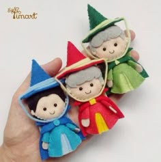 two small dolls are held in the palm of someone's hand, one is wearing an elf costume