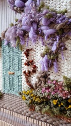 a close up of a wall hanging with flowers on it and a door in the background