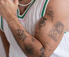 a man with many tattoos on his arm holding a cell phone to his ear and looking at the camera