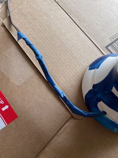 a pair of scissors sitting on top of a cardboard box next to a blue and white ball