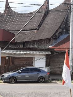 a car parked in front of a building with an orange and white flag next to it