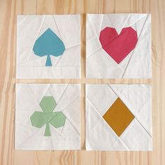 four pieces of paper with different shapes and colors on them sitting on a wooden surface