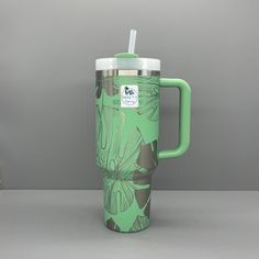 a green travel mug with a straw in it