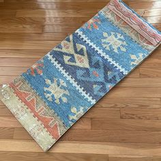 a blue and red rug on the floor with wood floors in the background, looking like it has been made from an old carpet