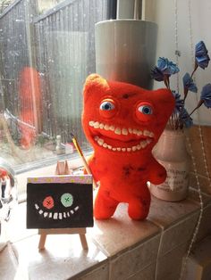 a red stuffed animal sitting on top of a window sill next to a sign