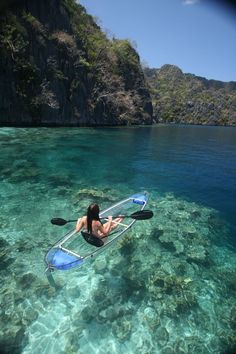 a man is paddling his kayak in the clear blue water near an island