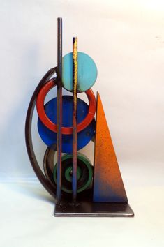 an artistic sculpture made out of various colored discs and other items on a white background