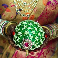 a close up of a person's hand holding a green brooch