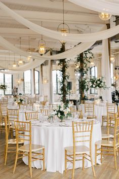 the tables are set with white linens and gold chairs for an elegant wedding reception