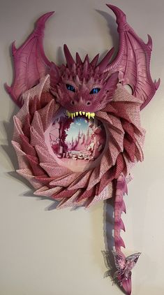 a pink dragon sculpture hanging on the wall