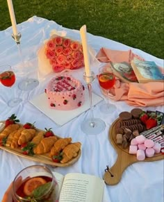 a table topped with cakes and desserts next to wine glasses on top of a field