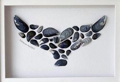 a white frame with some rocks and shells in the shape of a heart on it