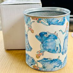 a blue and white canister sitting on top of a table next to a box