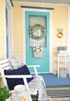 a front porch with a blue door and white rocking chair