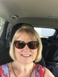 a woman wearing sunglasses sitting in the back seat of a car