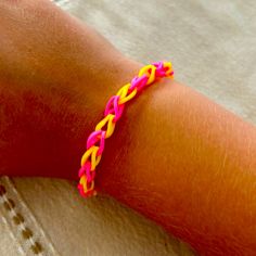 a person wearing a pink and yellow bracelet on their arm