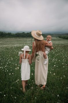 two women and a baby walking through a field