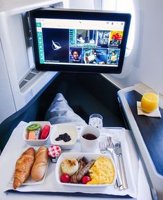 an airplane tray with food on it and a tv in the back ground behind it