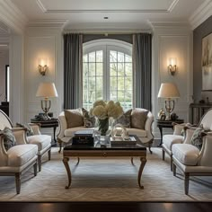 a living room filled with lots of furniture next to two lamps and a table in front of a window