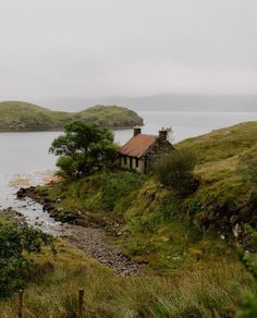 an old house sitting on top of a hill next to a body of water