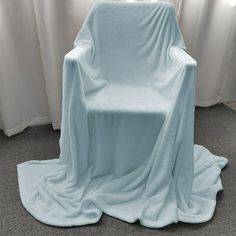 a blue chair covered with a blanket in front of a window