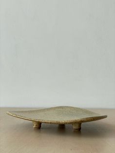 a ceramic plate sitting on top of a wooden table in front of a white wall