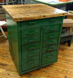 a kitchen island made out of an old green cabinet and some chairs in the background