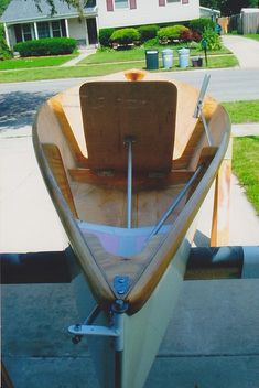 a small wooden boat sitting on the side of a road in front of a house