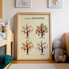 a cross stitch tree is displayed in front of two framed pictures on the wall next to a teddy bear