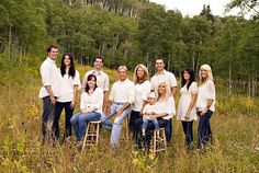 a group of people posing for a photo in a field with tall grass and trees