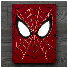 a spider - man face with glowing eyes on a wooden wall mounted paneled in wood planks