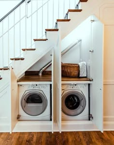 a washer and dryer under the stairs in a home with wood flooring