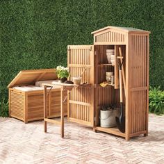 a wooden garden shed sitting on top of a brick floor next to a green wall