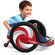 a young boy is riding on a toy car with wheels and steering wheel, while smiling at the camera