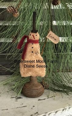 a snowman ornament hanging from a pine tree