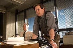 two men are in an office setting with papers on the desk