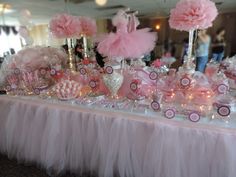 a table topped with lots of pink and white candy bar decorations on top of a table