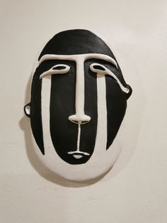 a black and white mask hanging on the wall