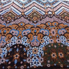 an intricately designed piece of cloth with blue, brown and white designs on it