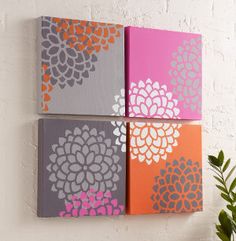 three canvases are hanging on the wall with flowers painted on them, one is pink and gray