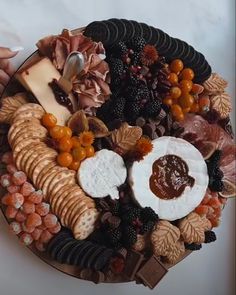 a platter with cheese, crackers, fruit and nuts on it is shown