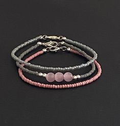 Set of 3 stackable beaded bracelets. Wear one or wear all 3. The first bracelets is a medium grey seed bead with 3 pink 6mm glass beads with 3mm silver beads on either side. The second bracelet is a dusty pink and the third bracelet is a smoky light grey. The lobster claw and jump rings are silver plated. Grey Necklace, Stackable Beaded Bracelets, Stick Earrings, Beading Wire, Beaded Choker Necklace, Seed Bead Necklace, Pink Beads, Silver Drop Earrings, Beads Bracelet