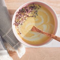 a white bowl filled with soup next to a wooden spoon on top of a table