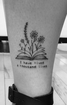 a black and white photo of an open book with flowers on it, reading i have lived a thousand lives