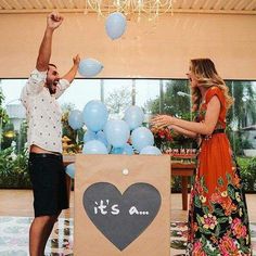 a man and woman standing in front of a box with balloons