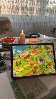 a tablet computer sitting on top of a table next to a candle and some papers