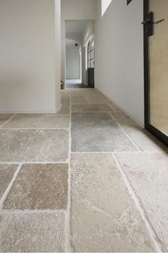 an empty hallway with white walls and stone flooring