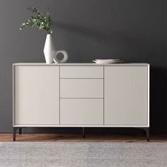 a white vase sitting on top of a wooden cabinet